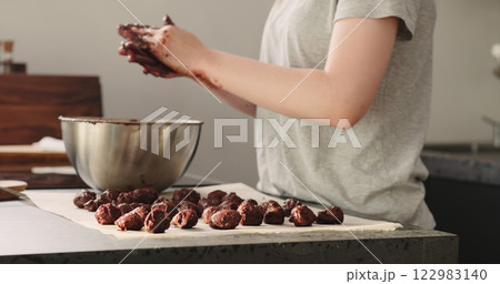 young woman making chocolate truffles on home kictchen 122983140