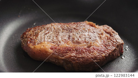 Closeup shot of ribeye steak frying on non stick pan Closeup shot of ribeye steak frying on non stick pan 122983144