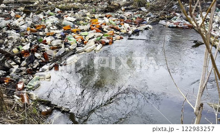 Dirty river is polluted with many plastic bottles. A lot of trash is dumped in open and freely available places at nature. Global environmental pollution problem. Concept of ecological disaster 122983257