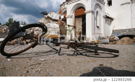 View to burned bike against the background of destroyed church at Kharkivska oblast. Ruined building after bomb attacks on ukrainian territory from russia army. russian invasion of Ukraine. Slow View to burned bike against the background of destroyed church at Kharkivska oblast. Ruined building after bomb attacks on ukrainian territory from russia army. russian invasion of Ukraine. Slow 122983266