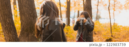 Banner Child taking picture her mother on retro camera in autumn park. Hobbies and leisure concept. Copy space 122983739