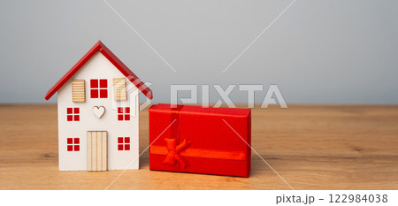 Miniature house and gift box. Housing as a gift. Win an apartment in the lottery. To inherit property. Holiday discounts. Buying an apartment at a low price. Sale of real estate. Present 122984038