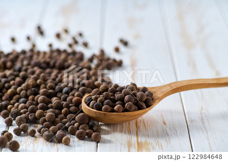 allspice or Jamaican pepper in a wooden spoon on a light kitchen table. allspice or Jamaican pepper in a wooden spoon on a light kitchen table. 122984648