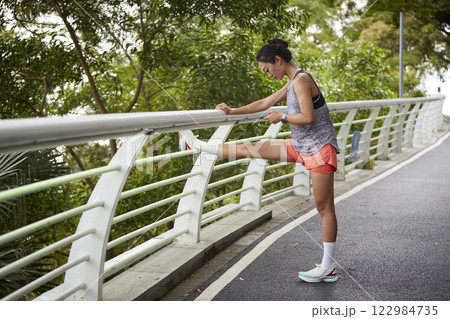 young asian woman pressing legs before exercising outdoors young asian woman pressing legs before exercising outdoors 122984735