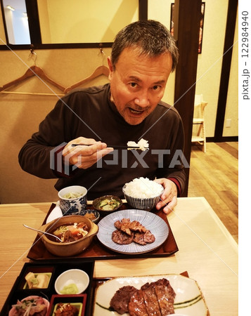 牛タン定食を美味しそうに食べる男性 122984940