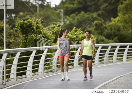 two young asian joggers chatting outdoors two young asian joggers chatting outdoors 122984997