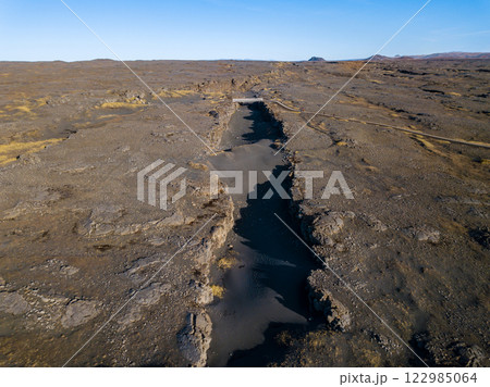 Aerial of the bridge connecting the north american and eurasian tectonic plates at Reykjanes, showcasing the dramatic rift between two major geological boundaries 122985064