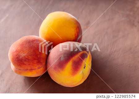 Fresh Peaches on Brown Background, Close-Up 122985574