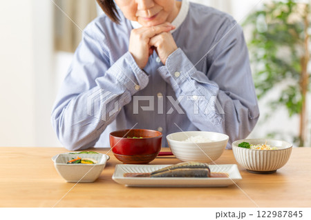 和食の朝食を前に悩むミドル女性 122987845
