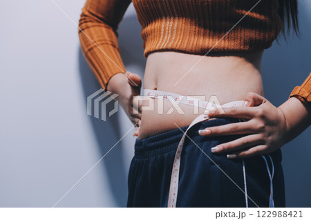 Asian Woman Pinching Her Belly Fat With Left Hand Asian Woman Pinching Her Belly Fat With Left Hand 122988421
