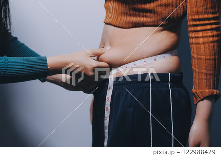 Asian Woman Pinching Her Belly Fat With Left Hand Asian Woman Pinching Her Belly Fat With Left Hand 122988429