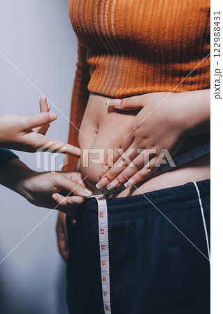 Asian Woman Pinching Her Belly Fat With Left Hand Asian Woman Pinching Her Belly Fat With Left Hand 122988431