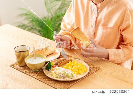 洋食の朝食でトーストを食べるミドル女性の手元 122988864