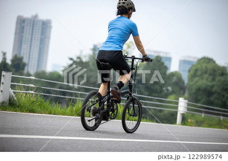 Riding a fold bike with modern city in the distrance 122989574
