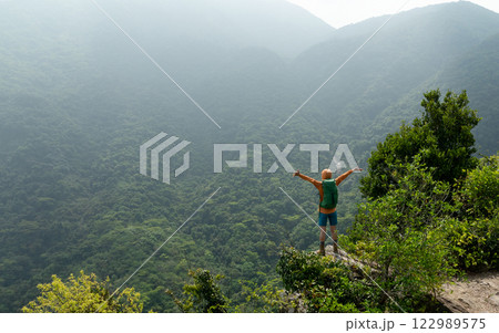 Young woman backpacker hiking at forest mountain top Young woman backpacker hiking at forest mountain top 122989575