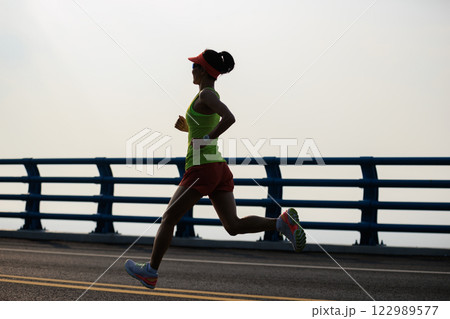 Healthy lifestyle woman runner running on seaside bridge Healthy lifestyle woman runner running on seaside bridge 122989577