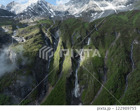 Aerial view of beautiful high altitude snow capped mountain and waterfall landscape Aerial view of beautiful high altitude snow capped mountain and waterfall landscape 122989755