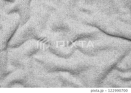 Close up texture of light gray crumpled woven fabric with a subtle pattern of evenly spaced tiny dots, providing a soft, neutral background ideal for design and creative projects 122990700