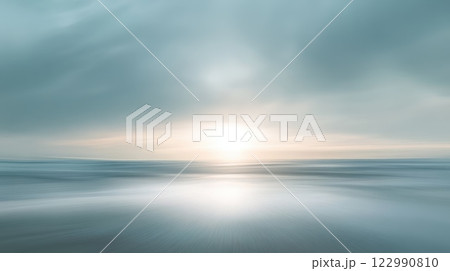 A beautiful blue ocean with a sun setting in the background 122990810