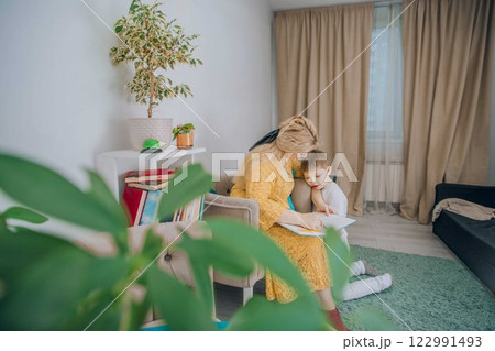 young boy listening to a woman reading concept of relaxation, comfort, and emotional connection in learning, plant young boy listening to a woman reading concept of relaxation, comfort, and emotional connection in learning, plant 122991493