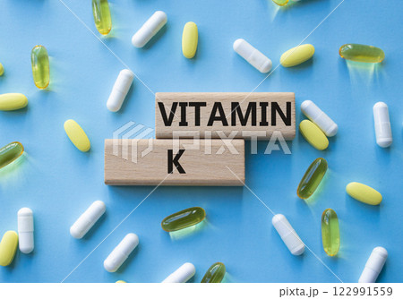 Vitamin K symbol. Concept word Vitamin K on wooden blocks. Beautiful pink background with pills. Medicine and Vitamin K concept. Copy space 122991559