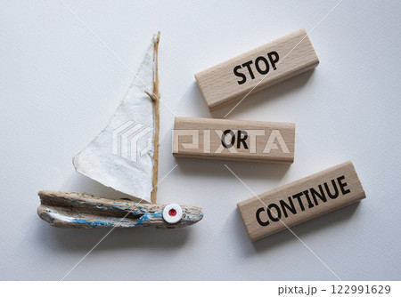 Stop or Continue symbol. Concept words Stop or Continue on wooden blocks. Beautiful white background with boat. Business concept and Stop or Continue. Copy space. 122991629