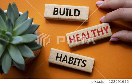 Healthy habits symbol. Concept word Build Healthy habits on wooden blocks. Doctor hand. Beautiful orange background with succulent plant. Healthy lifestyle and Healthy habits concept. Copy space Healthy habits symbol. Concept word Build Healthy habits on wooden blocks. Doctor hand. Beautiful orange background with succulent plant. Healthy lifestyle and Healthy habits concept. Copy space 122991636