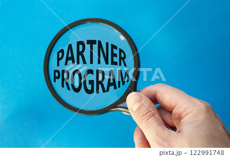 Partner Program symbol. Concept words Partner Program on magnifying glass. Businessman hand. Beautiful blue background. Business and Partner Program concept. Copy space. Partner Program symbol. Concept words Partner Program on magnifying glass. Businessman hand. Beautiful blue background. Business and Partner Program concept. Copy space. 122991748