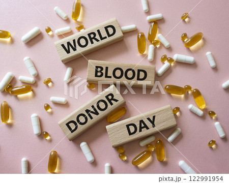 World Blood Donor Day symbol. Concept word World Blood Donor Day on wooden blocks. Beautiful pink background with pills. Medicine and World Blood Donor Day concept. Copy space World Blood Donor Day symbol. Concept word World Blood Donor Day on wooden blocks. Beautiful pink background with pills. Medicine and World Blood Donor Day concept. Copy space 122991954