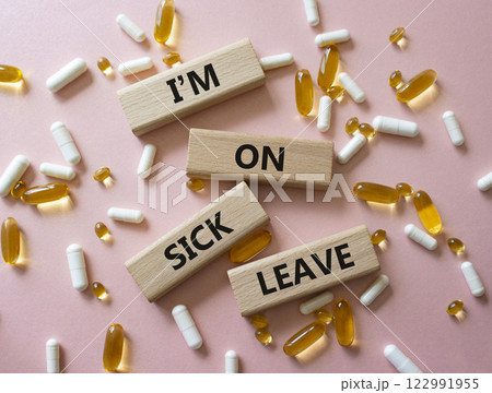Sick leave symbol. Concept word I am on sick leave on wooden blocks. Beautiful pink background with pills. Medicine and I am on sick leave concept. Copy space Sick leave symbol. Concept word I am on sick leave on wooden blocks. Beautiful pink background with pills. Medicine and I am on sick leave concept. Copy space 122991955