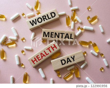 World Mental Health Day symbol. Concept word World Mental Health Day on wooden blocks. Beautiful pink background with pills. Medicine concept. Copy space World Mental Health Day symbol. Concept word World Mental Health Day on wooden blocks. Beautiful pink background with pills. Medicine concept. Copy space 122991956