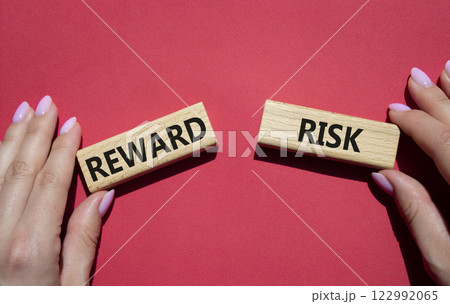 Risk or Reward symbol. Concept word Risk or Reward on wooden blocks. Businessman hand. Beautiful red background. Business and Risk or Reward concept. Copy space 122992065
