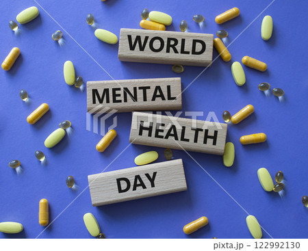World Mental Health Day symbol. Concept word World Mental Health Day on wooden blocks. Beautiful purple background with pills. Medicine concept. Copy space 122992130