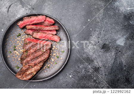 Grilled New York Striploin steak, perfectly seared with beautiful grill marks, showcasing its juicy tenderness and rich flavor. black background. top view Grilled New York Striploin steak, perfectly seared with beautiful grill marks, showcasing its juicy tenderness and rich flavor. black background. top view 122992162