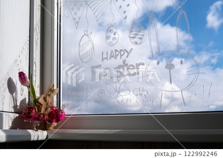 HAPPY EASTER text on creative painted window with white marker. Easter bunny rabbit decoration on big clear window. Springtime idea home decoration HAPPY EASTER text on creative painted window with white marker. Easter bunny rabbit decoration on big clear window. Springtime idea home decoration 122992246
