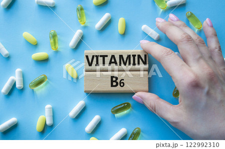 Vitamin B6 symbol. Concept word Vitamin B6 on wooden blocks. Beautiful blue background with pills. Doctor Hand. Medicine and Vitamin B6 concept. Copy space 122992310