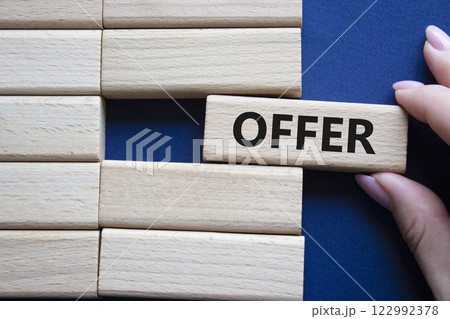 Offer symbol. Concept word offer on wooden blocks. Beautiful deep blue background. Businessman hand. Business and offer concept. Copy space. Offer symbol. Concept word offer on wooden blocks. Beautiful deep blue background. Businessman hand. Business and offer concept. Copy space. 122992378