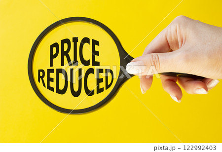 Price reduced symbol. Magnifying Glass with Concept word Price reduced. Beautiful yellow background. Businessman hand. Business and Price reduced concept. Copy space Price reduced symbol. Magnifying Glass with Concept word Price reduced. Beautiful yellow background. Businessman hand. Business and Price reduced concept. Copy space 122992403