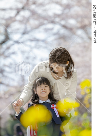 桜と菜の花の咲く公園を楽しむ入学の娘と母親 122992424