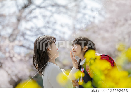 桜と菜の花の咲く公園を楽しむ入学の娘と母親 122992428