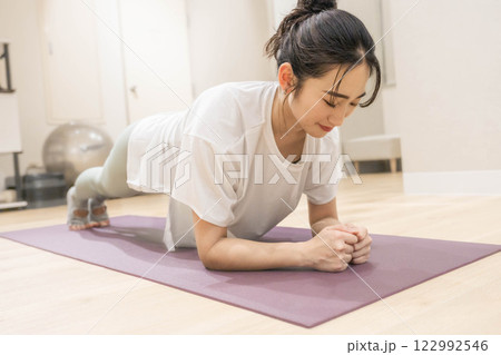 室内のジムで筋肉トレーニングをする若い女性 室内のジムで筋肉トレーニングをする若い女性 122992546