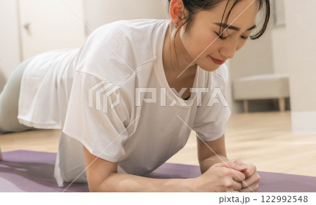 室内のジムで筋肉トレーニングをする若い女性 122992548