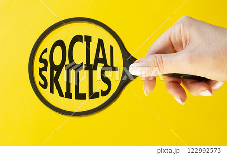 Social skills symbol. Concept words Social skills on magnifying glass. Beautiful yellow background. Businessman hand. Business and Social skills concept. Copy space. 122992573