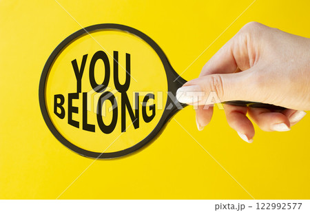 You belong symbol. Concept words You belong on magnifying glass. Beautiful yellow background. Businessman hand. Business and You belong concept. Copy space. 122992577