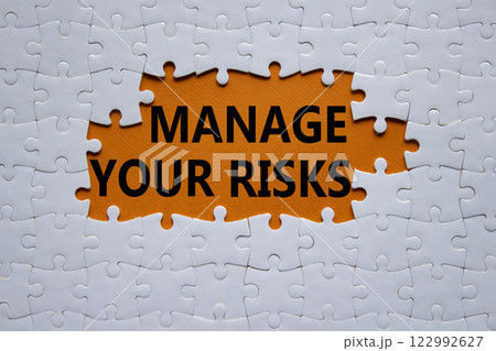 Risks symbol. Concept words Manage your Risks on white puzzle. Beautiful orange background Business and Manage your Risks concept. Copy space. 122992627