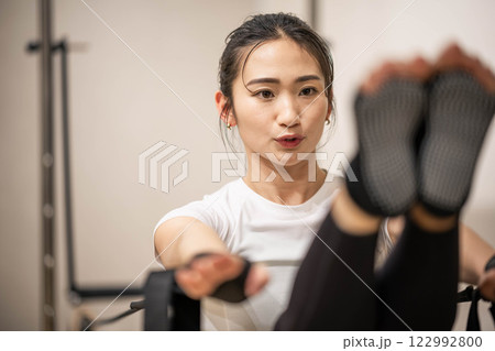 室内のジムでマシンピラティスをする若い女性 122992800