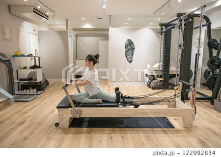 室内のジムでマシンピラティスをする若い女性 122992834