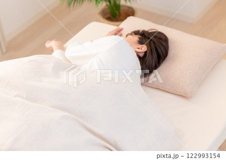 朝の寝室で熟睡する白いパジャマ姿のミドル女性 122993154