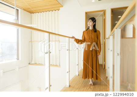 吹き抜けのある注文住宅と女性　 122994010