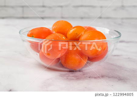 Frozen tomatoes in transparent bowl, on light background. Preservation of vegetables. Natural products 122994805